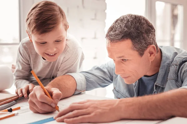 Blonde-haired son watching his father drawing figures for geometry class