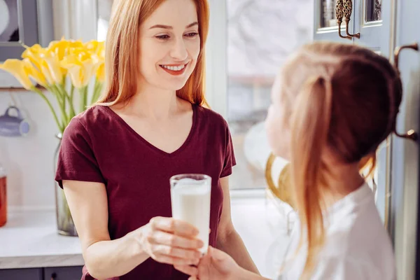 Красивая женщина улыбается и держит стакан молока для ребенка — стоковое фото