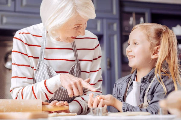 Felice donna anziana indicando i biscotti nelle mani di sua nipote — Foto Stock