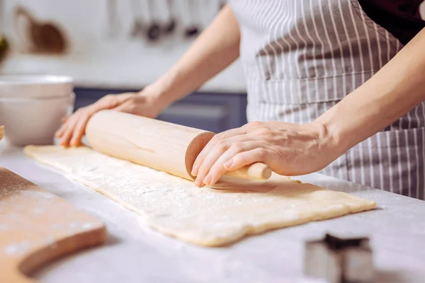 Tangan muda pada pin kayu membuat kue lezat di dapur — Stok Foto