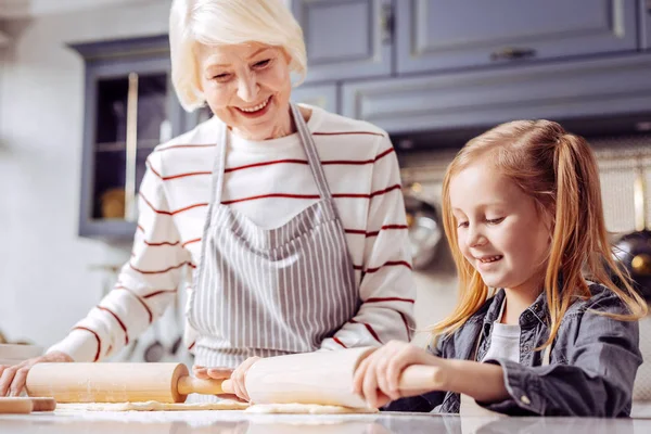 Mignonne fille tenant rouleau en bois pendant la cuisson avec grand-mère — Photo