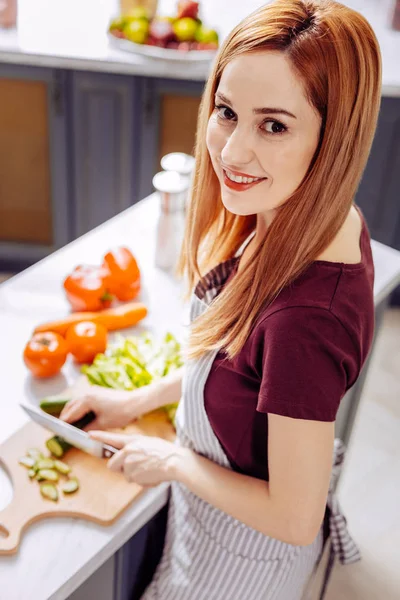 Beautiful woman holding knife in her left hand and cutting cucumbers — Stock Photo, Image