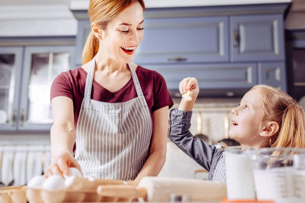 Glückliche Mutter schaut auf die Kekse in der Hand ihres Kindes — Stockfoto