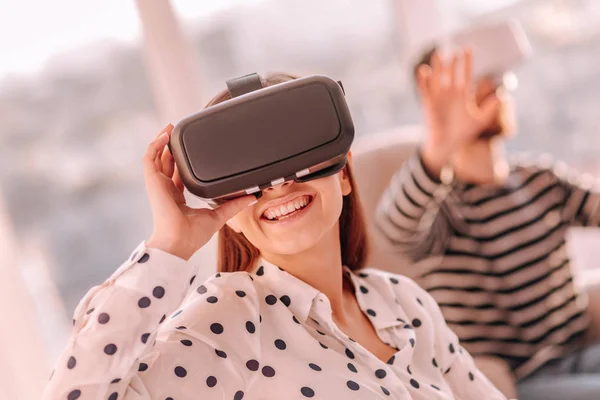 Smiling woman testing virtual reality device with friend