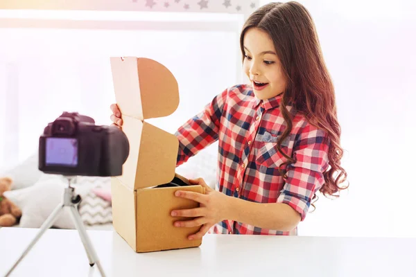 Chica emocional de ojos oscuros se siente extremadamente sorprendida después de abrir su caja actual — Foto de Stock