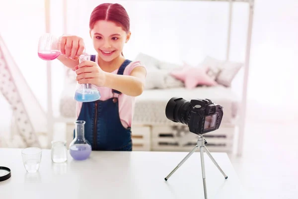 Lachende weinig blogger met behulp van de stand van de camera tijdens het filmen van chemie experiment — Stockfoto