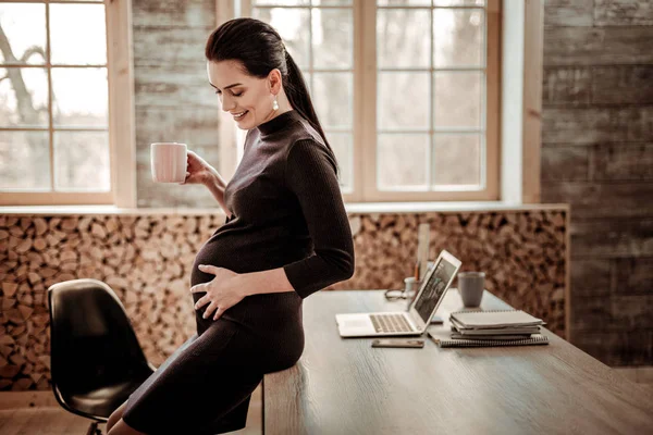 Mujer embarazada encantada tomando una taza de té — Foto de Stock