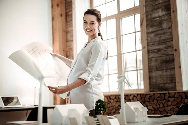 Mujer embarazada alegre sosteniendo un plano profesional — Foto de Stock