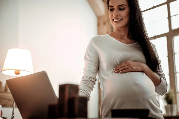 Aardige gelukkige vrouw die werkt tijdens haar zwangerschap — Stockfoto
