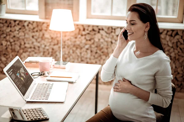 Delighted professional pregnant businesswoman answering the call — Stock Photo, Image