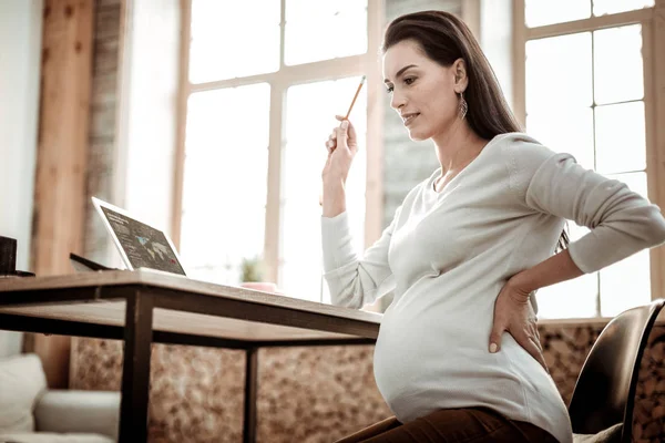 Pleasant smart pregnant woman thinking about her work — Stock Photo, Image