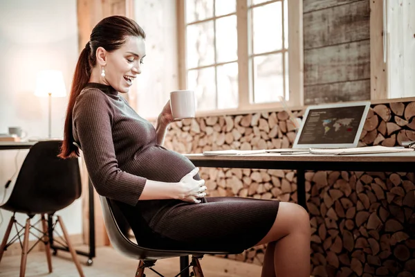 Joyful happy pregnant woman looking at her belly — Stock Photo, Image