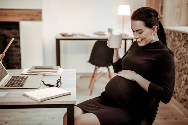 Veselou příjemnou těhotná žena odpočívá v kanceláři — Stock fotografie