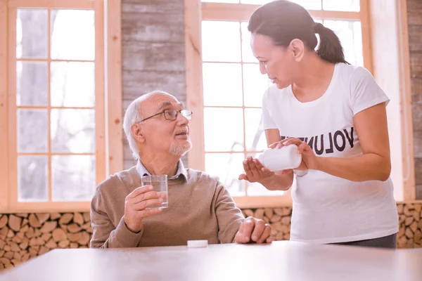 Attentive bearded pensioner listening to his helper — Stock Photo, Image