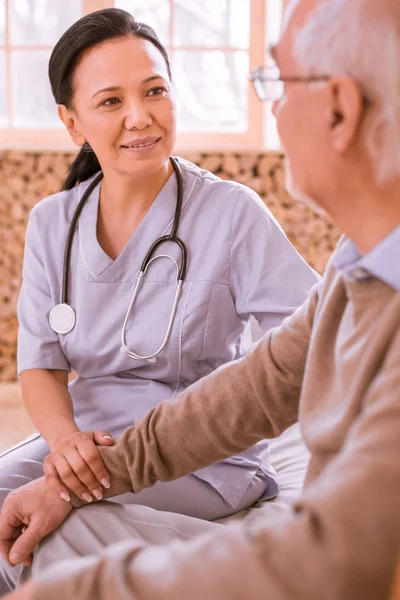 Mujer morena amable apoyando a su paciente senior — Foto de Stock