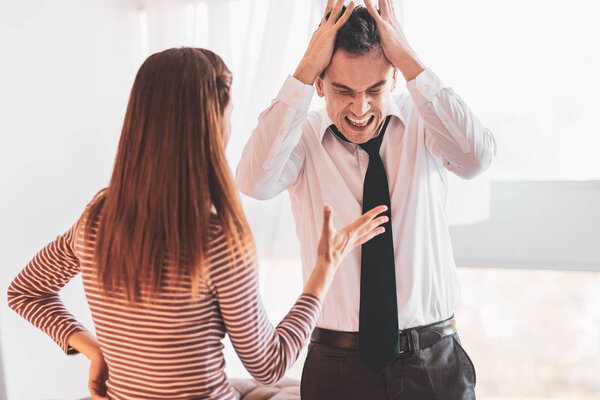 Expressive jobless man shouting while his wife feeling angry