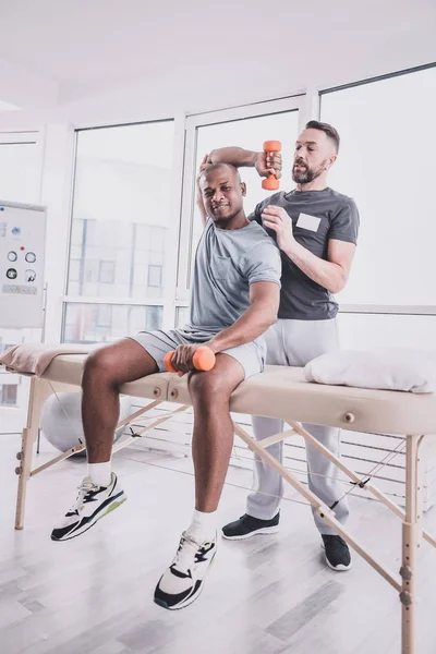 Attente bebaarde therapeut ter ondersteuning van zijn jonge sporter — Stockfoto