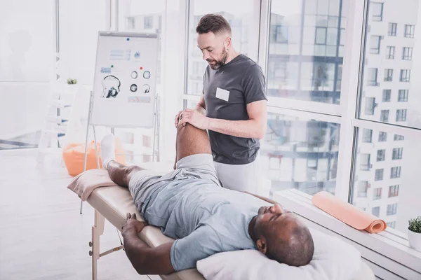 Profissional praticante fazendo massagem de reabilitação no joelho — Fotografia de Stock