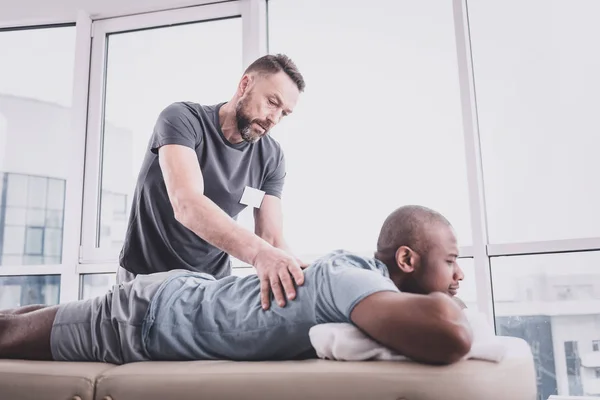 Homem barbudo atento fazendo massagem ao seu paciente — Fotografia de Stock