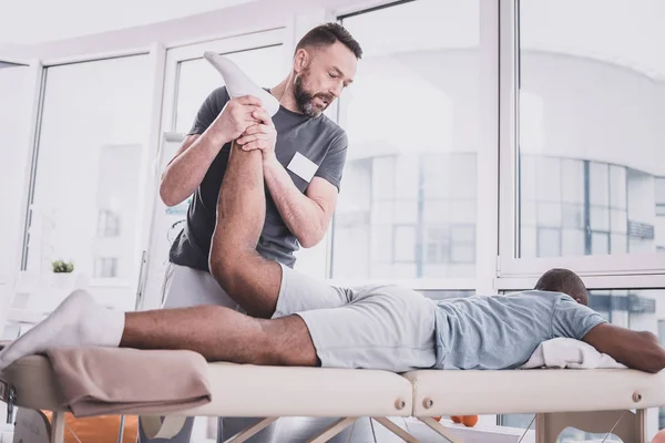 Strong bearded man doing rehabilitation procedure for muscles — Stock Photo, Image