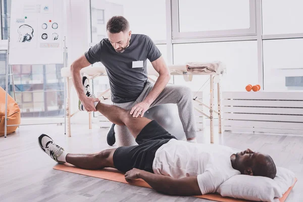 Konsentrat praktisi memeriksa otot pada kaki terluka — Stok Foto
