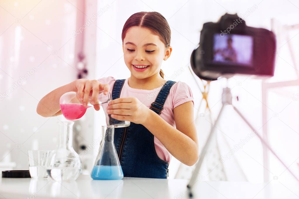Little girl wearing jeans jumper suit making chemistry experiment