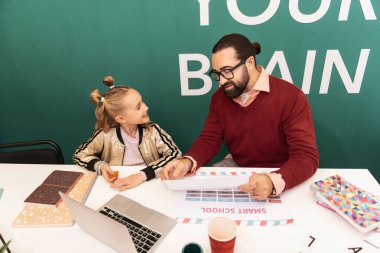 İyi bir ruh hali. Sevimli sarışın kız öğretmeni için gülümseyerek elini üzerinde Bilezik takıyor