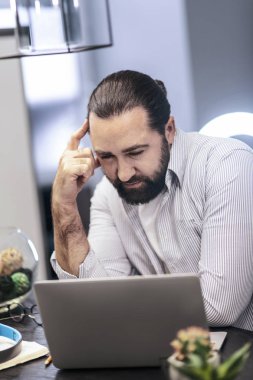 Düşünme süreci. Koyu renk saçlı sakallı adamın ciddi seyir çizgili bir gömlek giydiğini