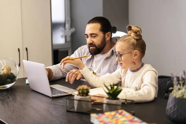 Dark-haired bearded teacher in a striped shirt doing home task with his pupil — Stock Photo, Image