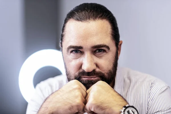 Dark-haired bearded man in a striped shirt looking concentrated — Stock Photo, Image