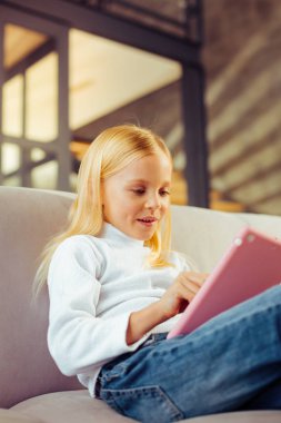 Onun tablet ile oynayan sevimli uzun saçlı çocuk