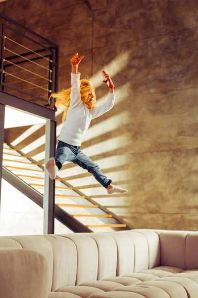 Активна дівчина стрибає на дивані у вітальні — стокове фото