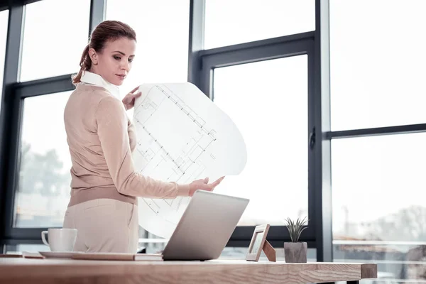 Delineador femenino profesional sintiéndose reflexivo mirando bocetos — Foto de Stock