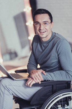 Happy disabled man sitting in front of his laptop clipart