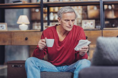Onun faturalarını küçük harflerle bakarak ve onları okumaya çalışıyorum ciddi adam