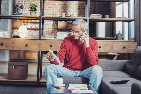 Hombre mayor mirando en serio mientras tiene una charla telefónica — Foto de Stock