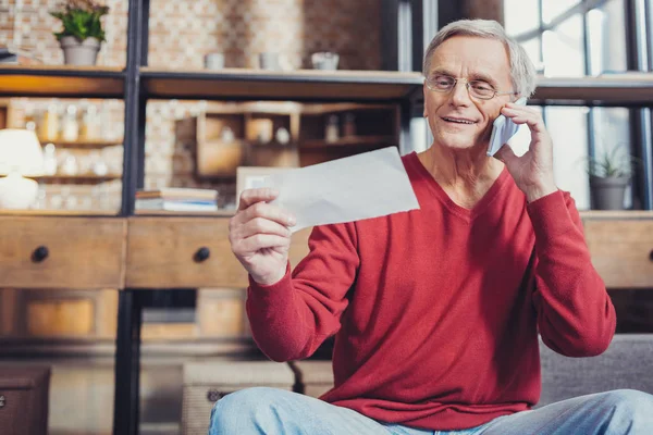 Весёлый пенсионер улыбается, когда звонит в банк — стоковое фото