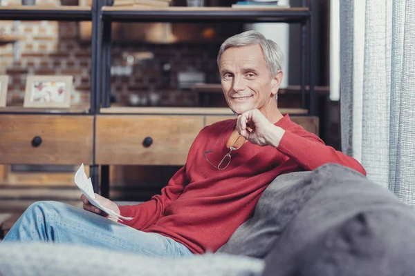 Neşeli emekli kanepede otururken gülümseyen — Stok fotoğraf