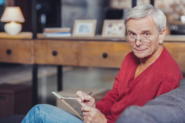 Pensionné inquiet prenant des notes dans son carnet et l'air impressionné — Photo