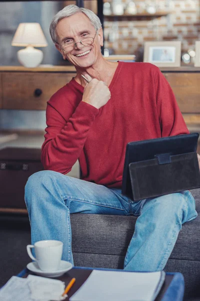 Feliz abuelo sonriendo mientras usa una tableta moderna de sus nietos — Foto de Stock