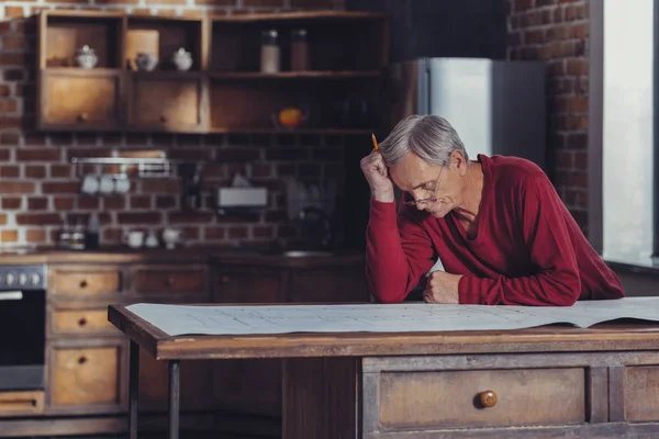 Serious gepensioneerde ingenieur kijkend naar de afbeelding en denken — Stockfoto