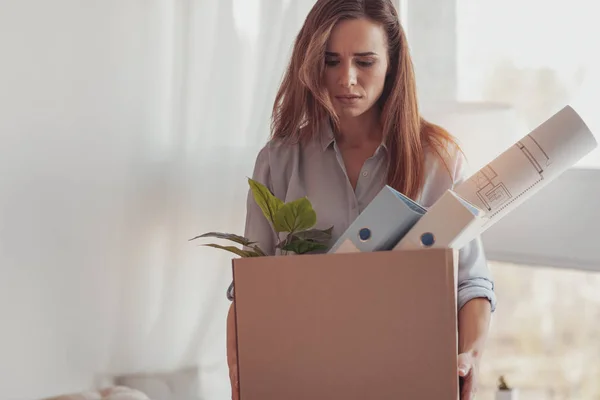 Грустная унылая женщина держит коробку со своими офисными вещами — стоковое фото