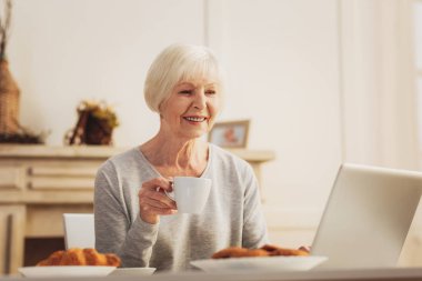 Sabah haber dizüstü bilgisayarda izlerken sıcak pasta yeme kadın