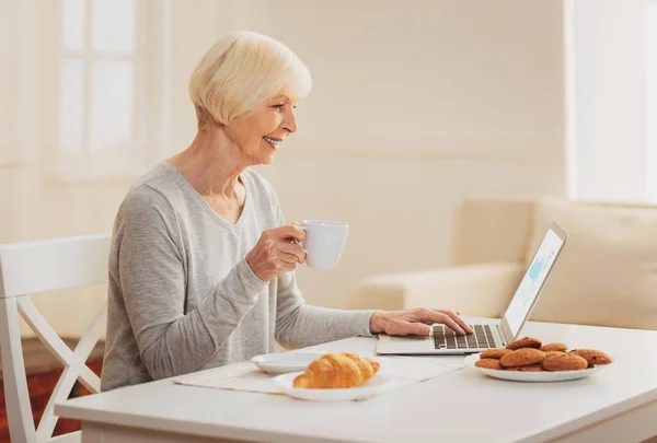 Mujer revisando e-mail mientras bebe té en la cocina — Foto de Stock