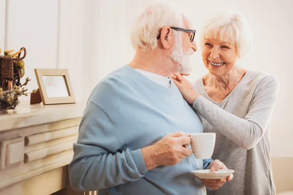 Anciana esposa abrazando a su amoroso hombre mientras toma el té — Foto de Stock