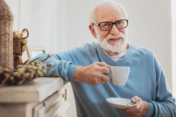 Smart elderly man drinking coffee while having break — Stock Photo, Image