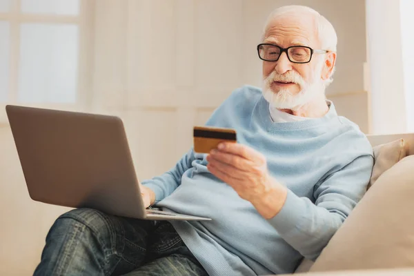 Modern elderly man paying for new furniture online
