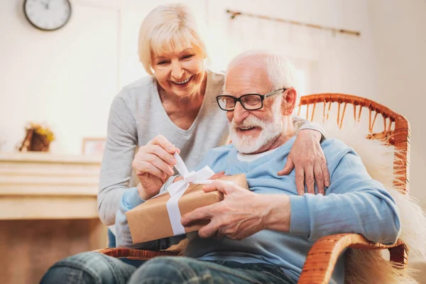 Smiling happy pensioner unpacking present for marriage anniversary