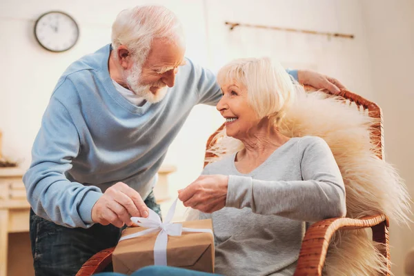 Fürsorglicher älterer Mann macht Geschenk für seine Geburtstagsfrau — Stockfoto