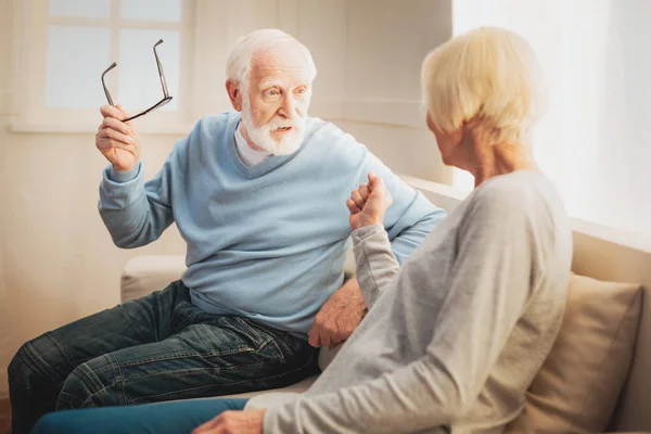 Un par de pensionistas hablando de asuntos familiares sentados en un sofá — Foto de Stock